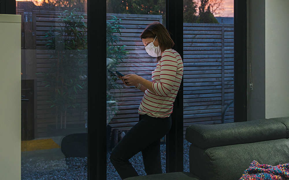 Woman in a mask looking at her phone.